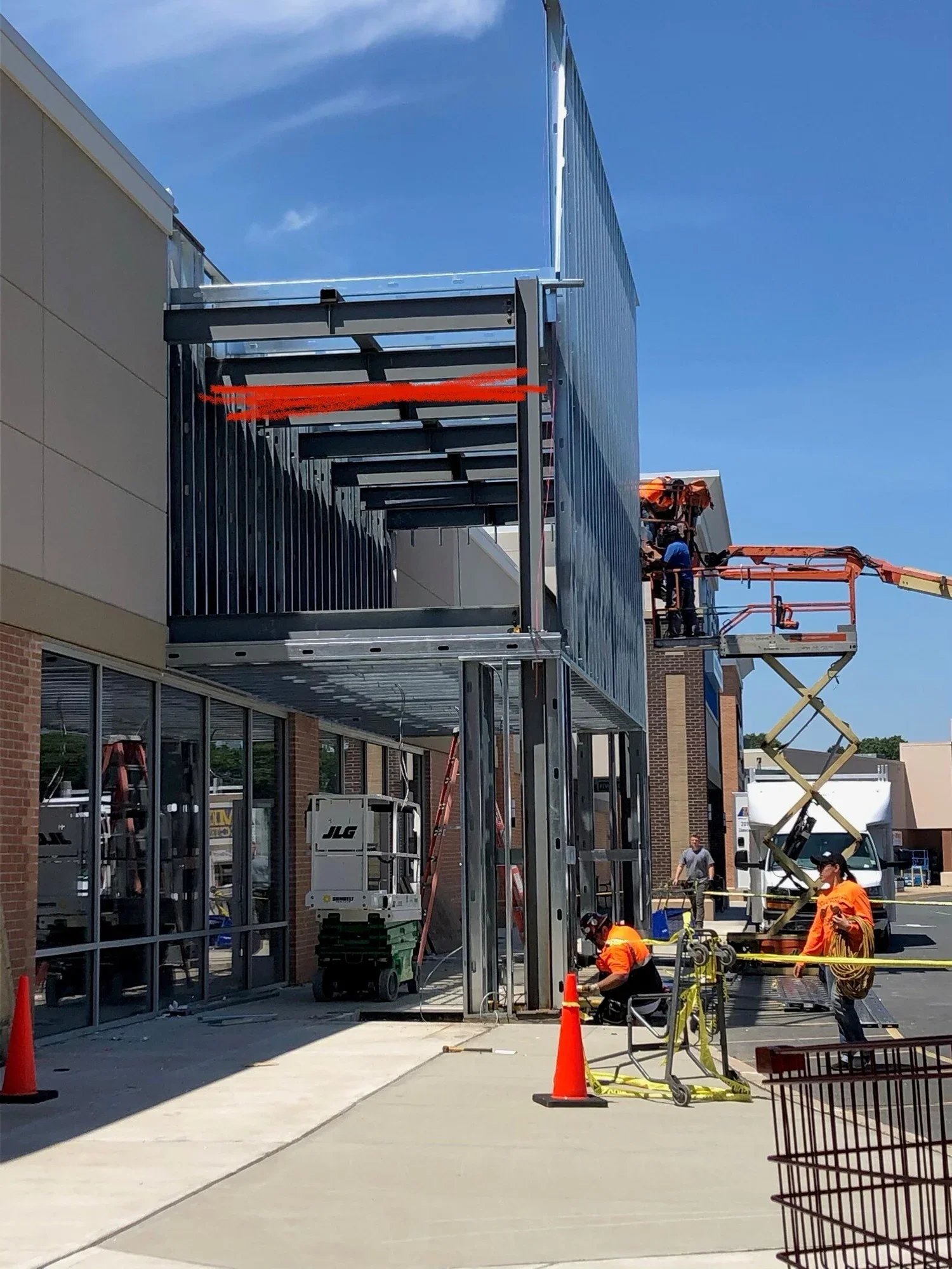 Crew on a scissor lift performing storefront facade and canopy electrical alterations